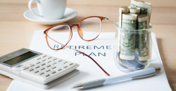 desk with a sheet of paper that says retirement plan with a pair of glasses coffee cup calculator pen and glass jar with cash inside tax strategies that could save your business thousands CJG Partners