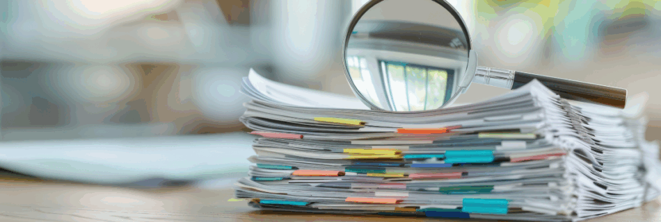 stack of papers with a magnifying glass sitting on top Audit Review Compilation Assurance