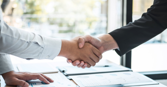two hands shaking over a desk of paperwork cjg partners Merger and Acquisition Strategic Roadmap for Mid-Market Businesses