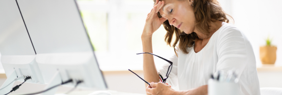 woman at a desk looking stressed out and holding her glasses with her head propped on her hand Post-Tax Season Bookkeeping Fix What Went Wrong Now cjg partners accounting cpa