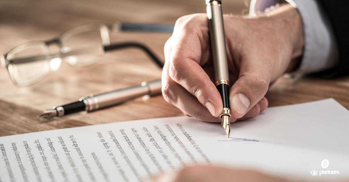 hand signing a document with a pair of glasses next to it What Your Audit Is Really Worth (Hint: It's More Than Compliance) CJG Partners