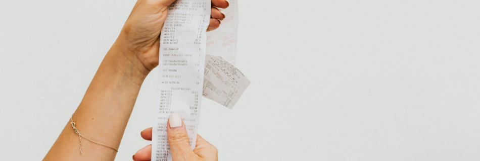 woman's hands holding a long receipt Behind on Bookkeeping? How to Get Back on Track By Year-End cjg partners