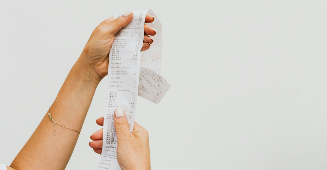woman's hands holding a long receipt Behind on Bookkeeping? How to Get Back on Track By Year-End cjg partners