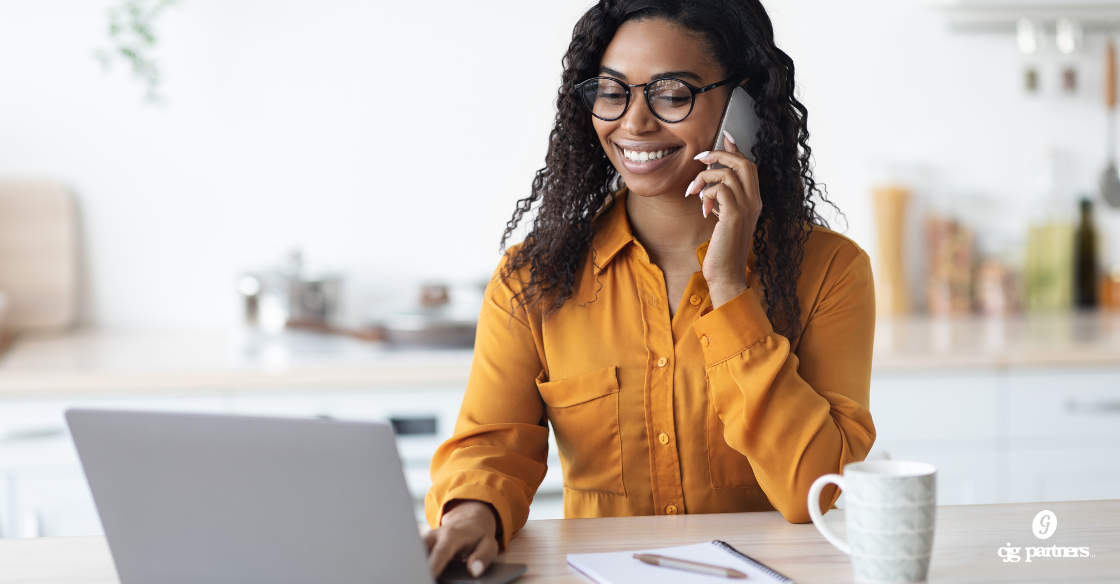 woman sitting at a table typing on a laptop and talking on a cell phone Hiring Independent Contractors? Get the Worker Classification Right cjg partners