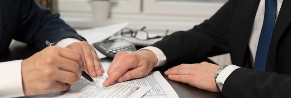 two men sitting at a desk pointing at papers Tax Planning vs. Tax Preparation: What's the Difference and Why It Matters cjg partners