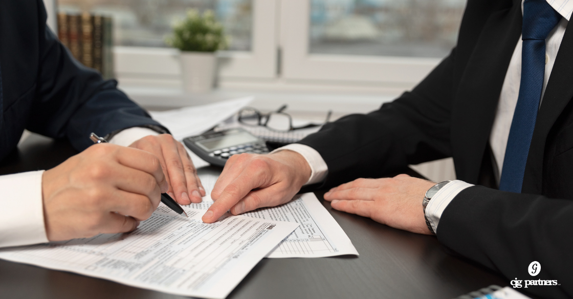 two men sitting at a desk pointing at papers Tax Planning vs. Tax Preparation: What's the Difference and Why It Matters cjg partners