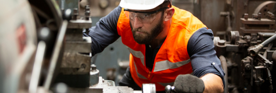 man wearing hard hat and orange vest working on a machine Bonus Depreciation and Section 179: What to Know Before You Buy Equipment