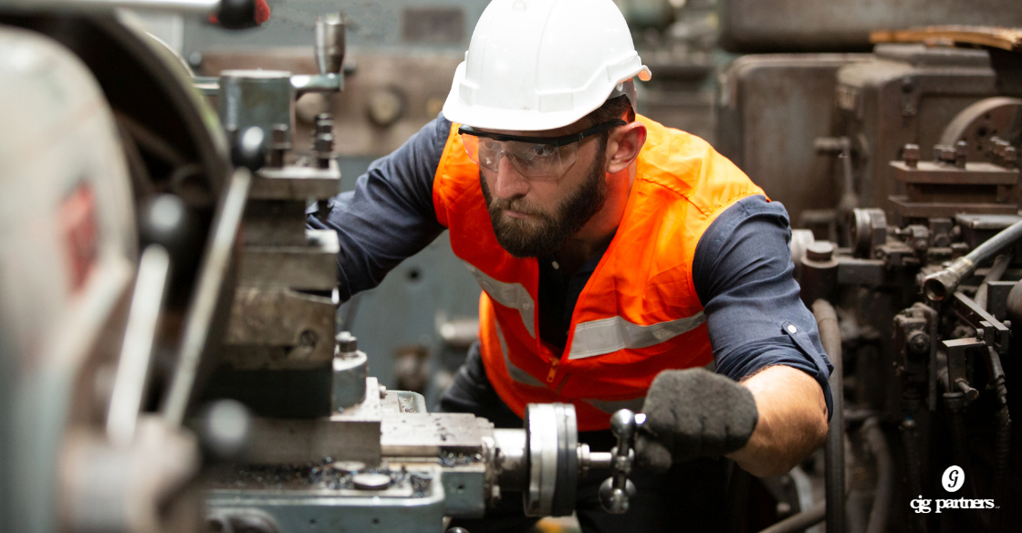 man wearing hard hat and orange vest working on a machine Bonus Depreciation and Section 179: What to Know Before You Buy Equipment