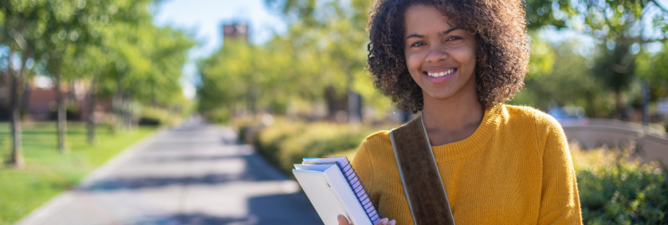 young black woman standing outside with a bookbag on her shoulder and holding a binder and a notebook Does College Financial Aid Count as Taxable Income?